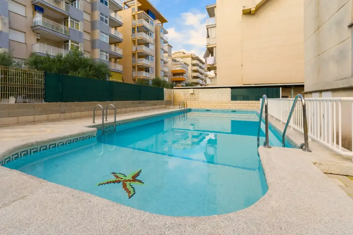 Una piscina al aire libre está rodeada de edificios de apartamentos.