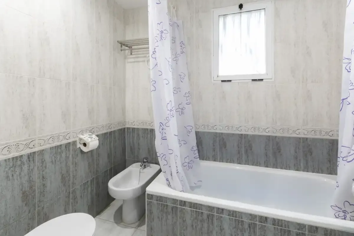 Un baño con bañera, bidé y ventana.