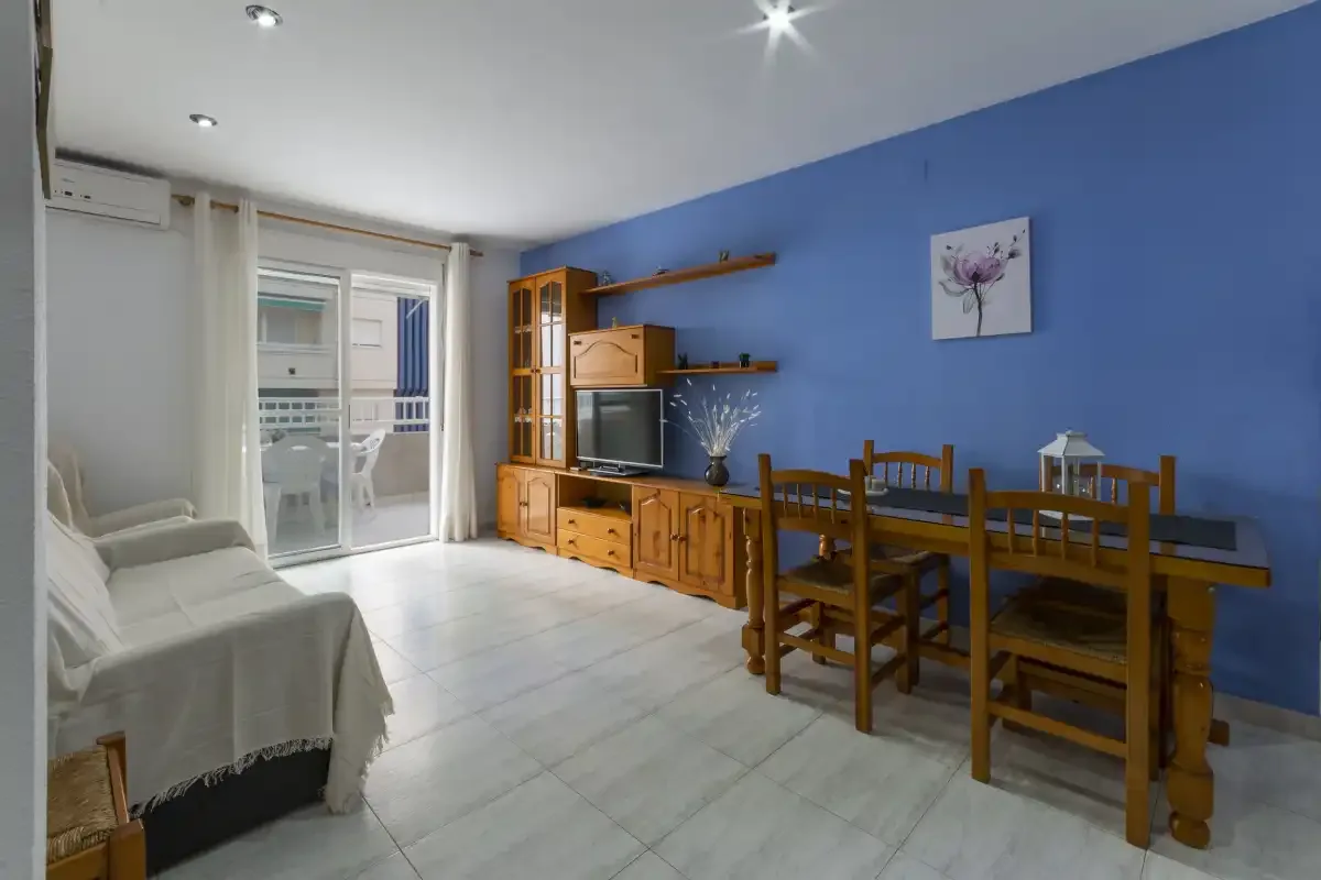 Una zona de estar y comedor con asientos de madera y una pared azul.