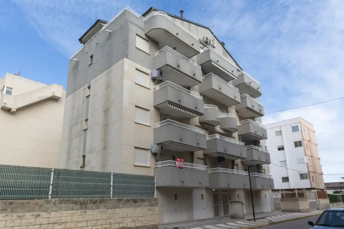 Un edificio de apartamentos de varias plantas con balcones está junto a una calle.