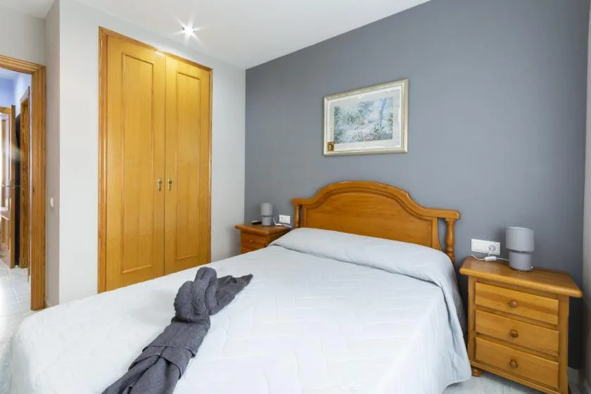 Un dormitorio con cama, cabecero de madera y mesitas de noche a juego.