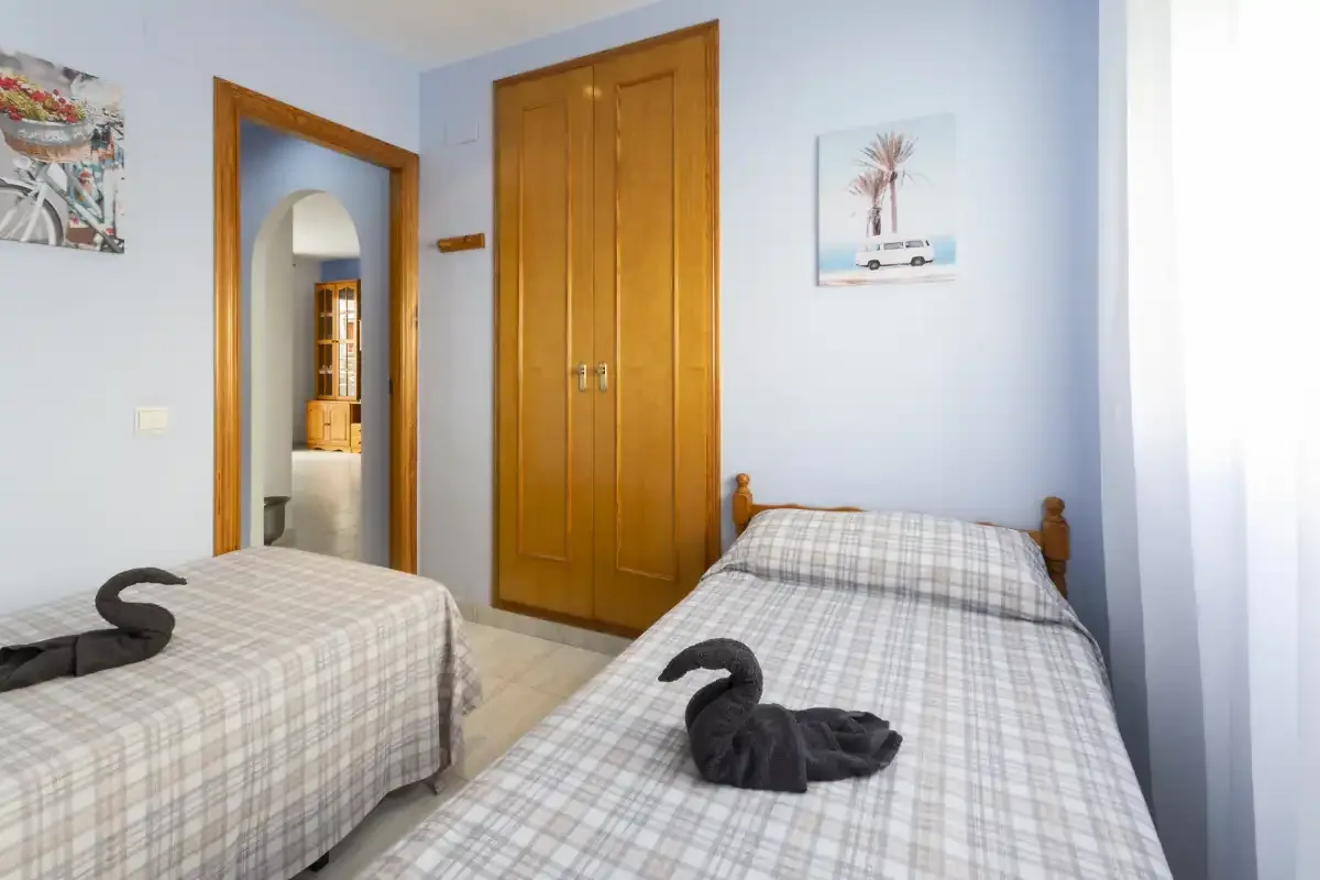 Dormitorio con dos camas y un armario de madera.