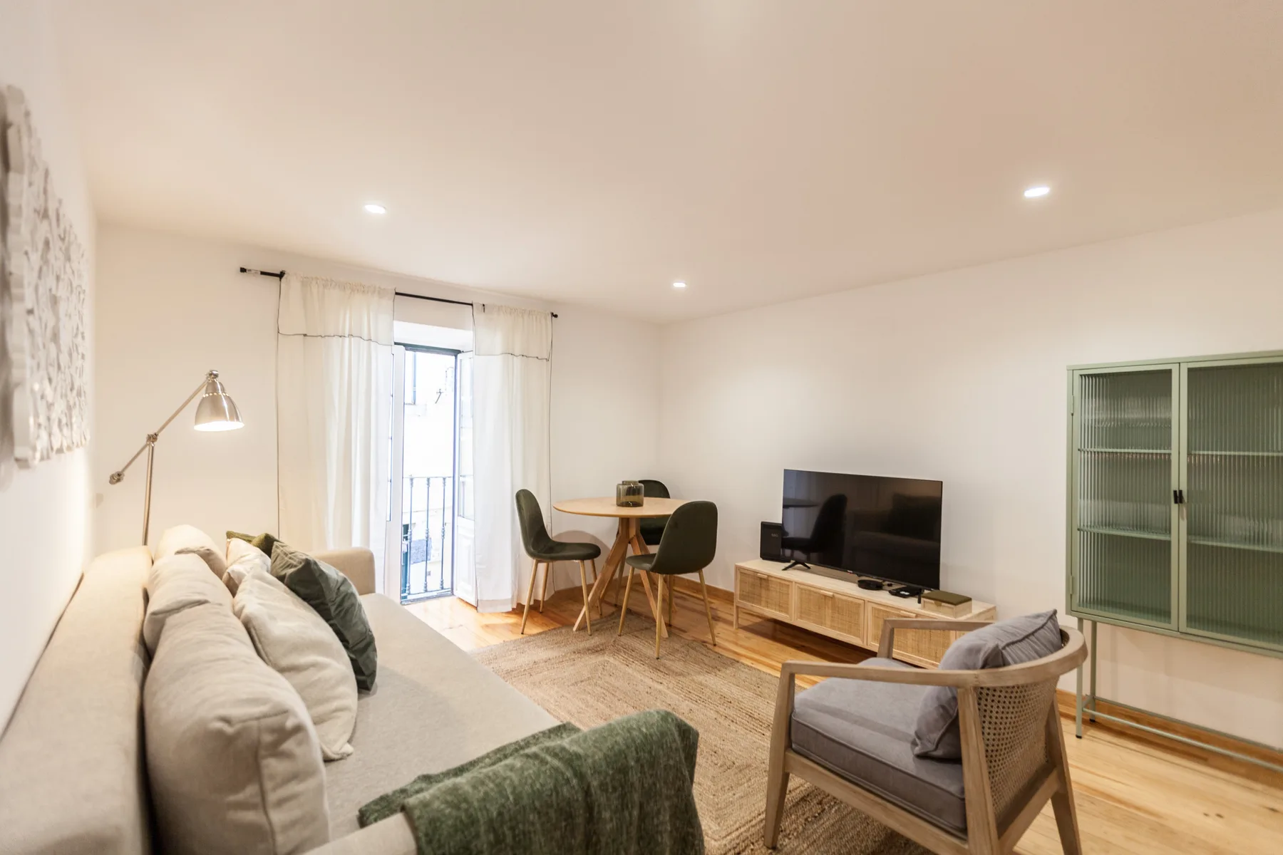 A bright living room with seating, a television, and a dining table.