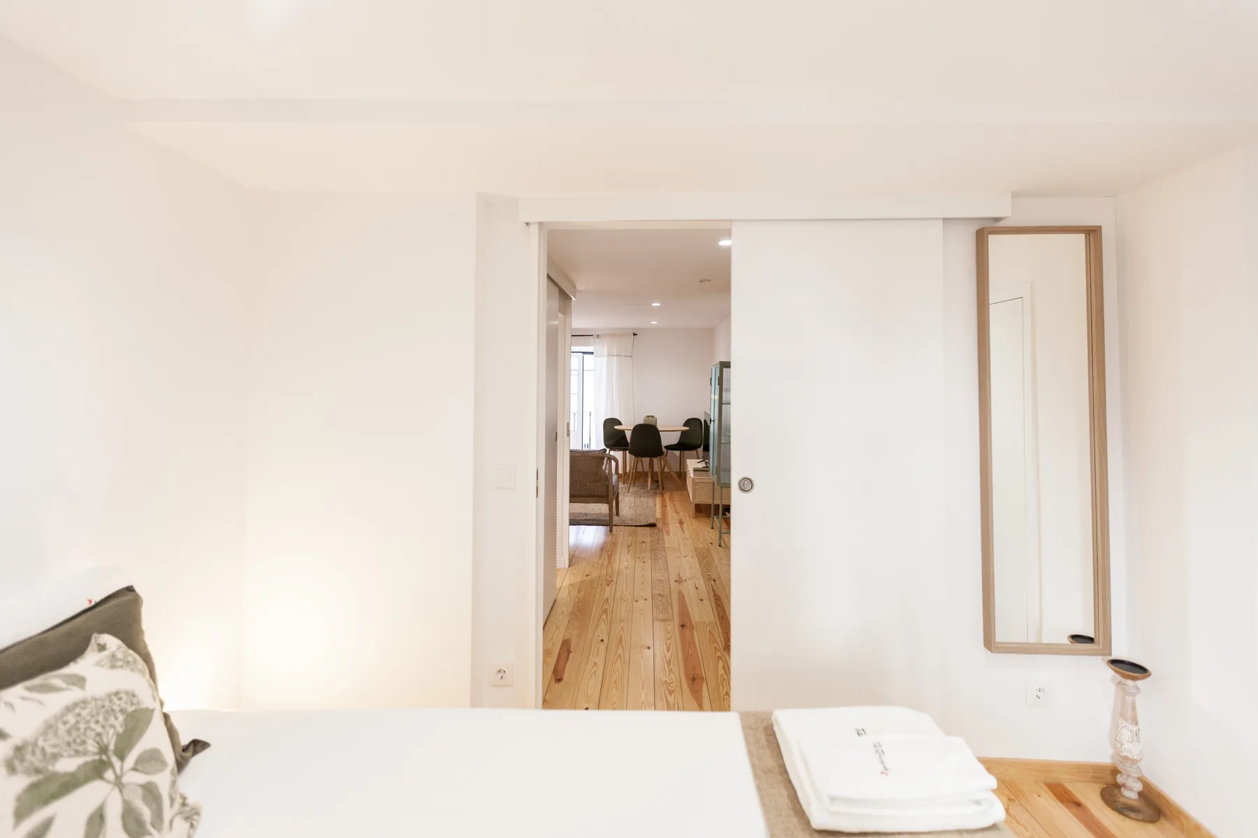 A bedroom opens onto a dining area with wooden flooring.