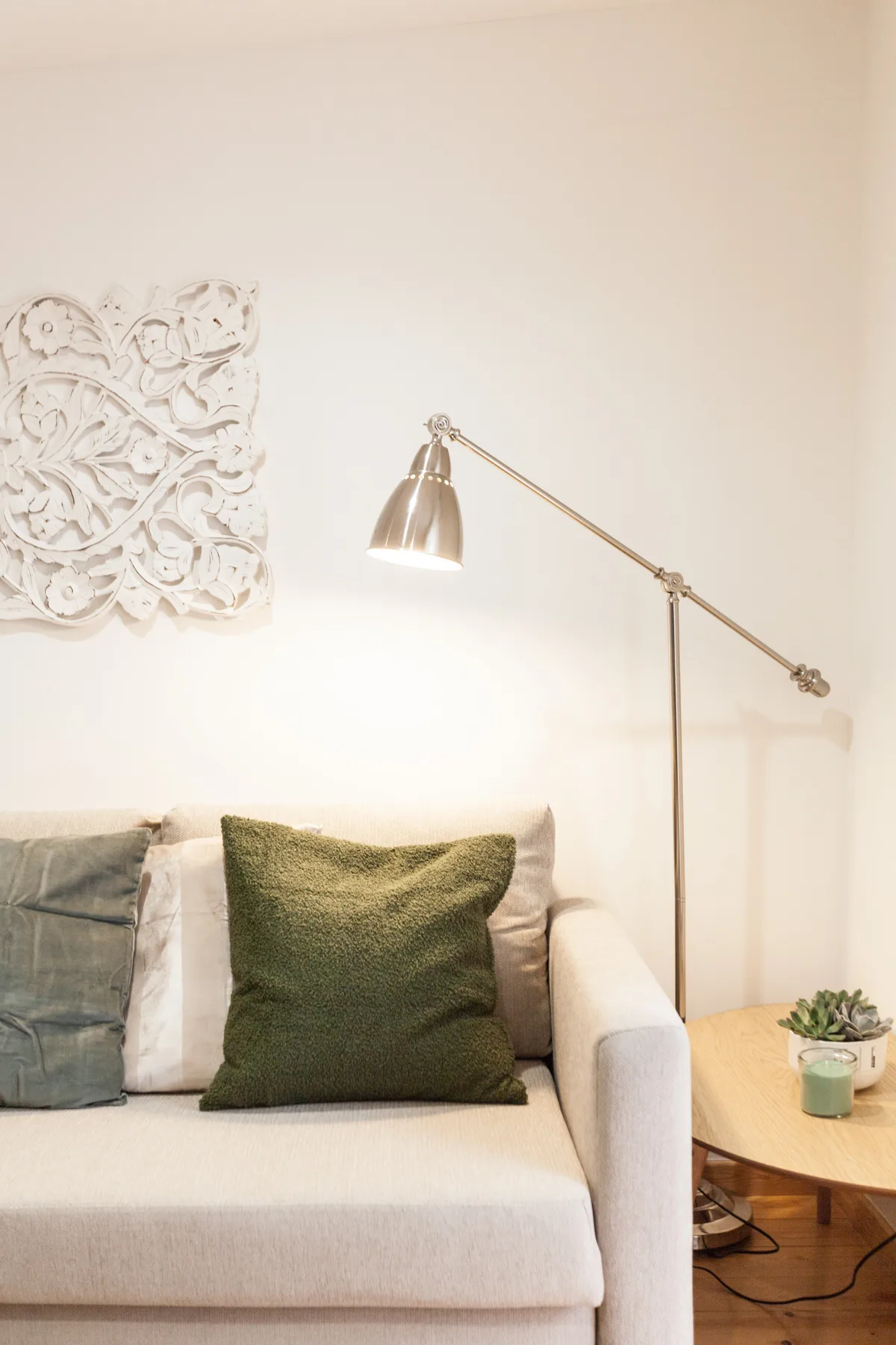 A living room seating area with cushions beside a floor lamp and small side table.