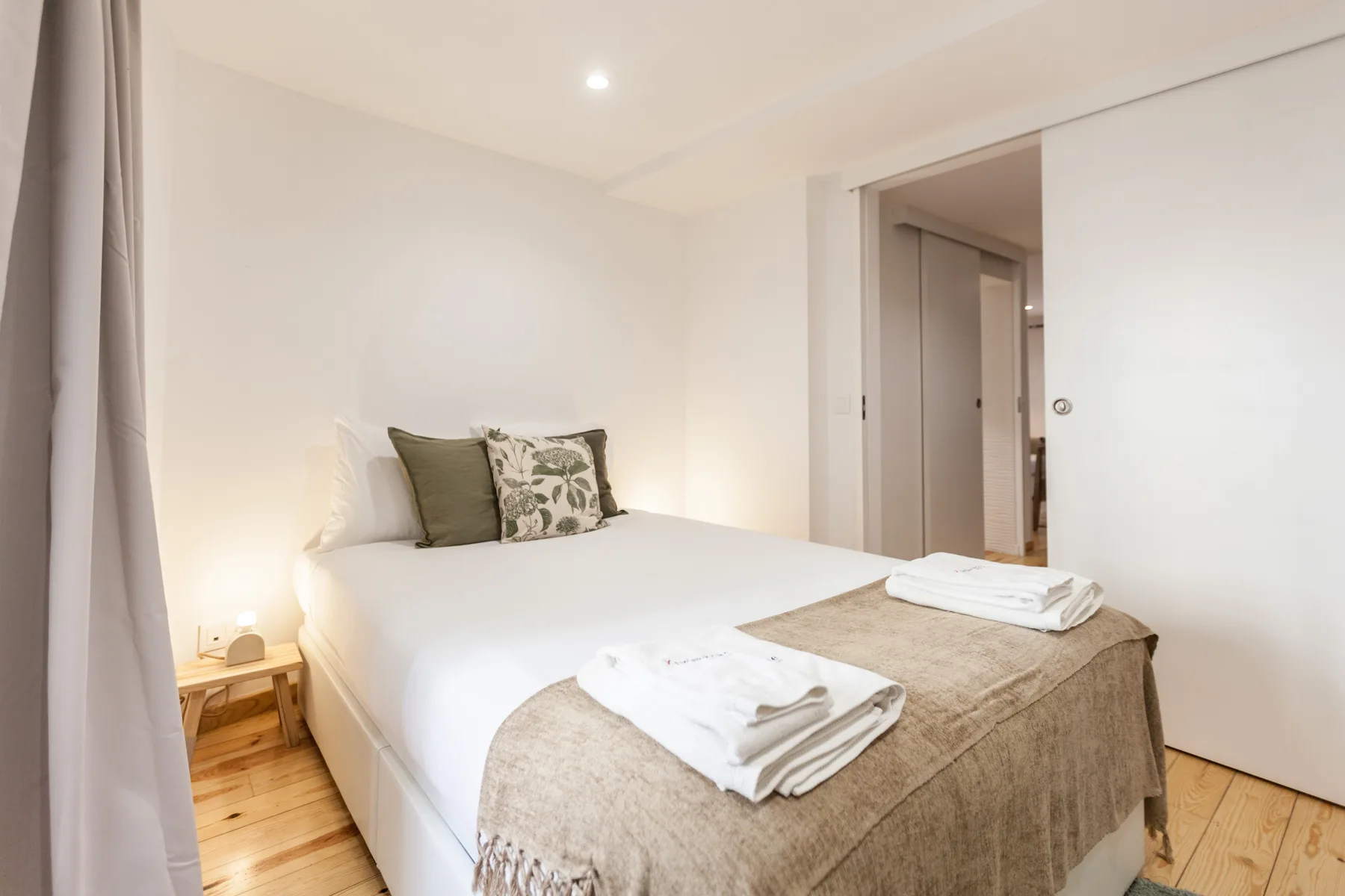 A bright bedroom with a neatly made bed and folded towels.