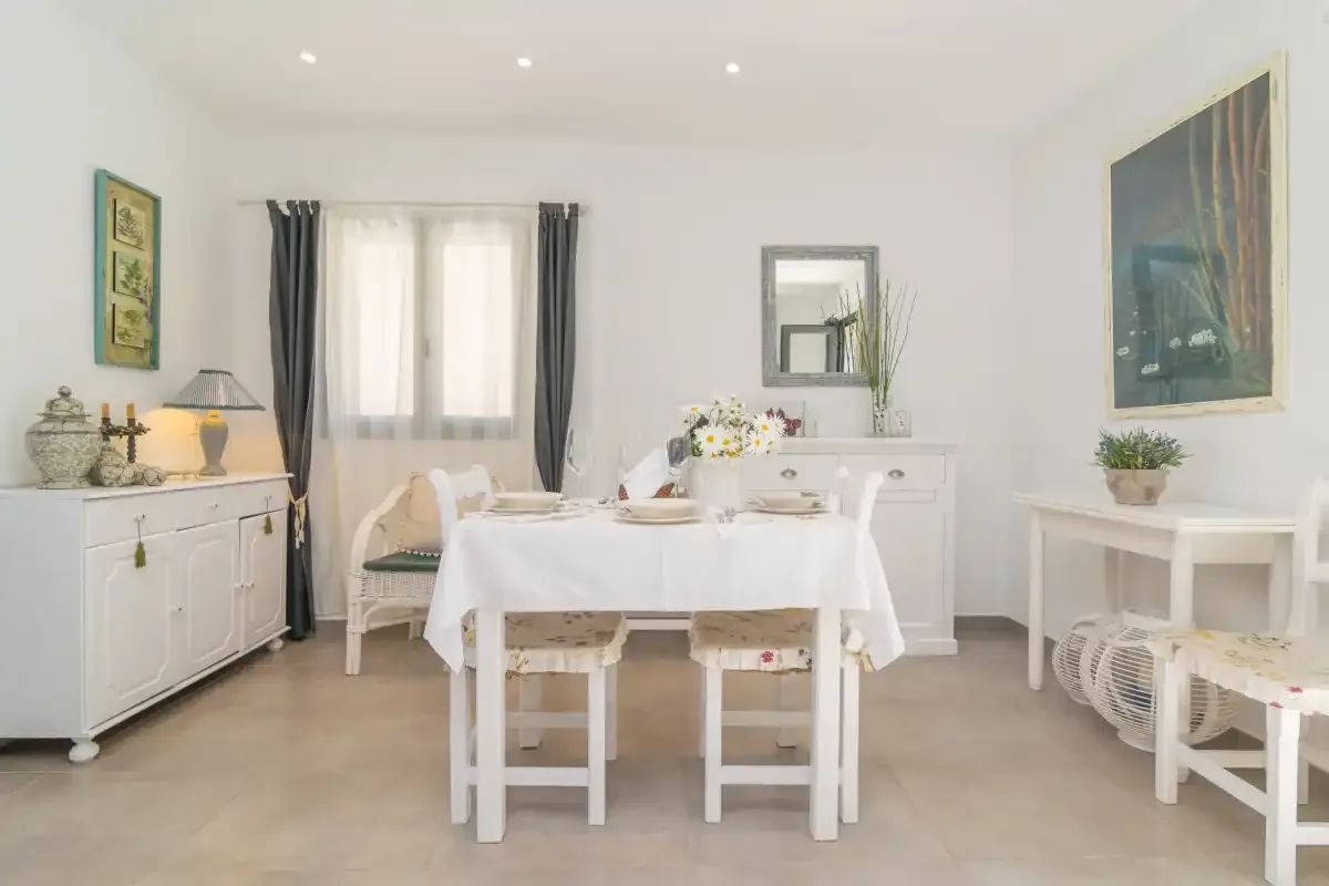Un comedor luminoso con una mesa blanca junto a una ventana con cortinas.