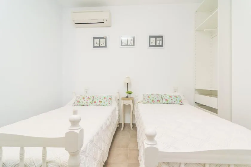 Un dormitorio luminoso con dos camas individuales y una mesita entre ellas.