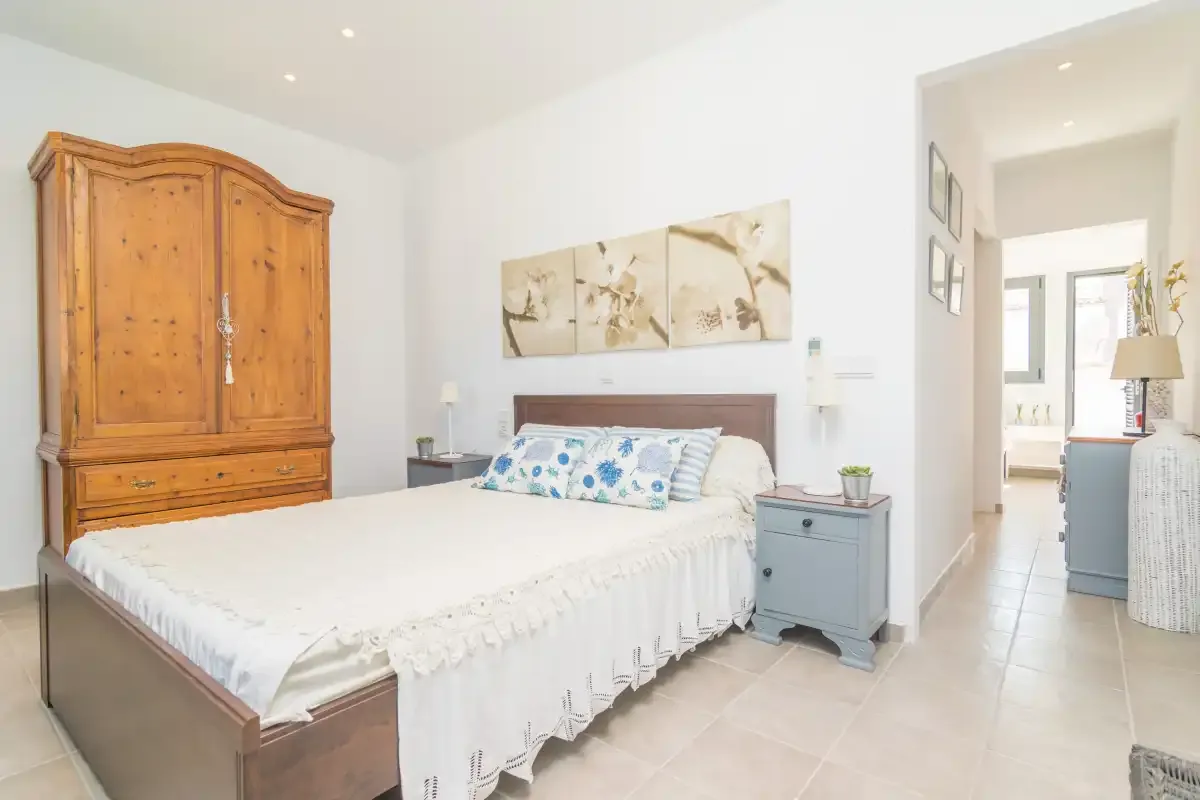 Un dormitorio luminoso con una cama, un armario de madera y una mesita de noche.