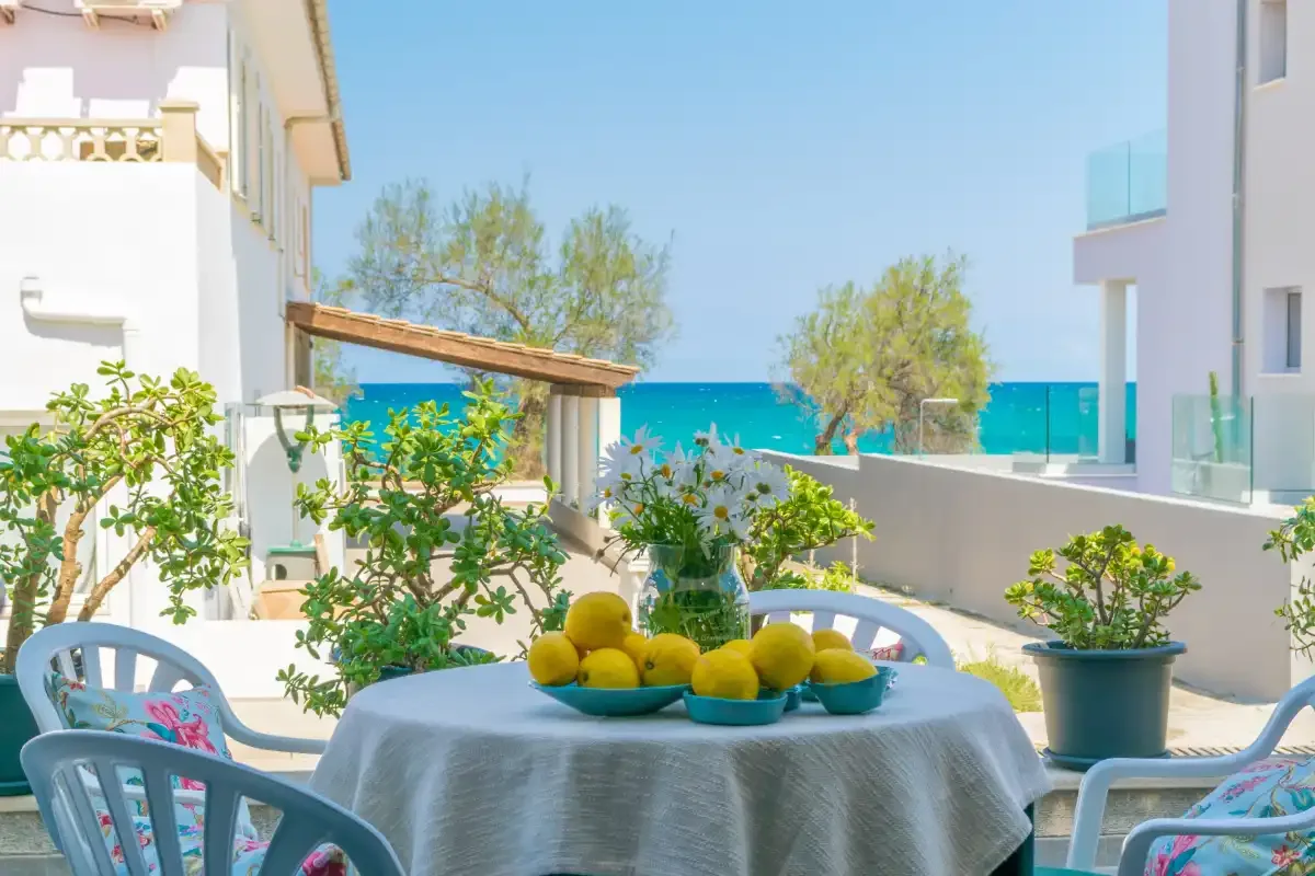 Un patio junto al mar con una mesa, asientos alrededor y vistas al mar.