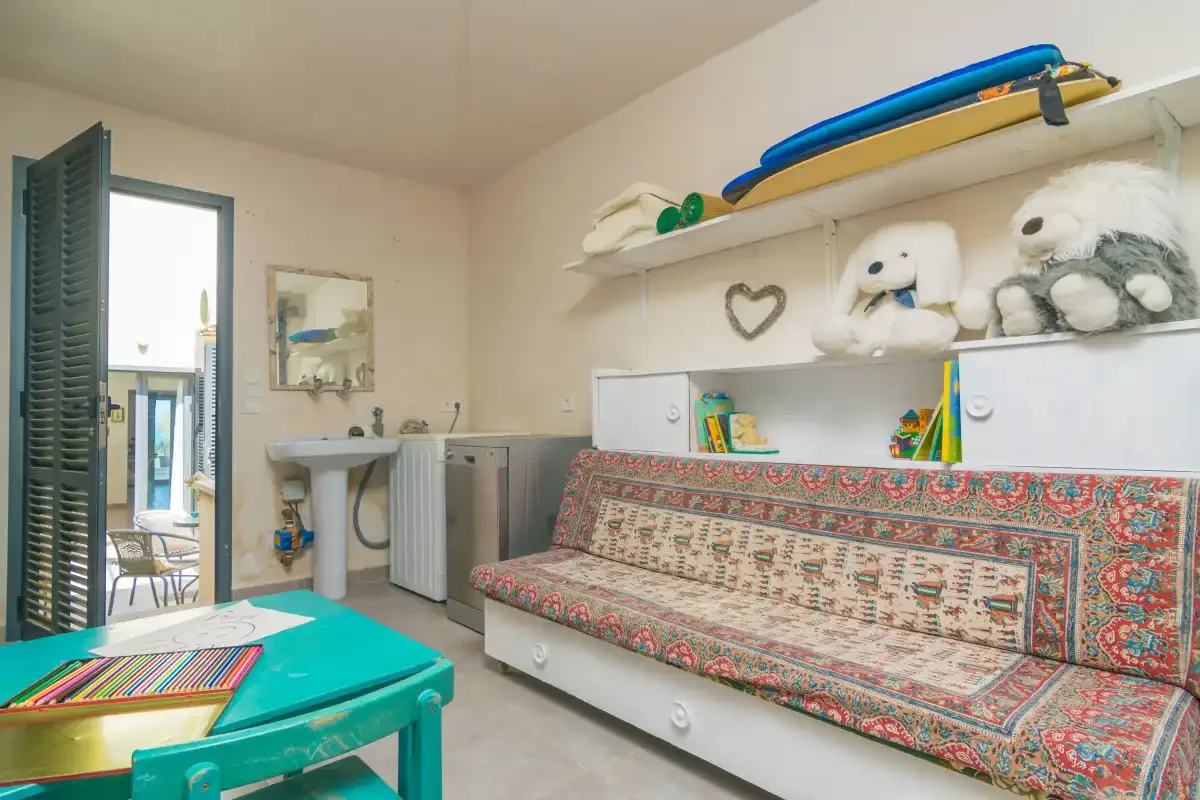 Una zona de estar con asiento estampado, estantes y una mesa turquesa.