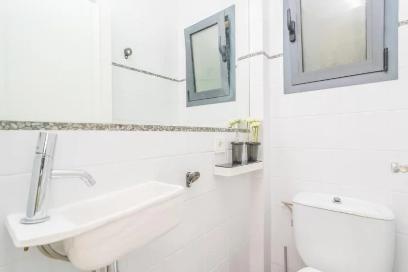 Un baño luminoso con paredes de azulejos, lavabo y retrete.