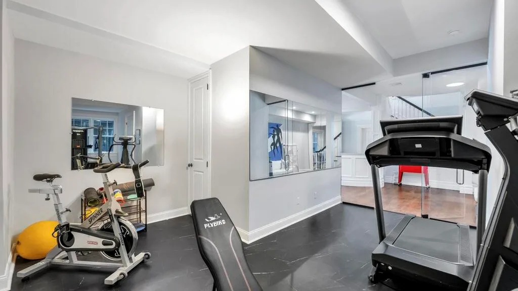 Un gimnasio en casa con equipo de ejercicio y un espejo grande.