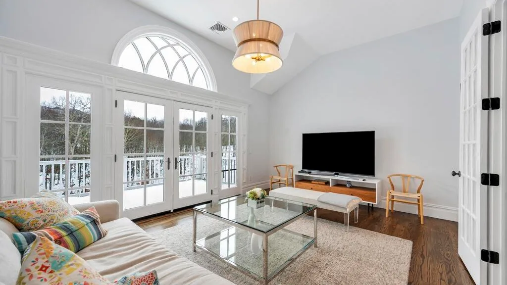 Una sala luminosa con una mesa de centro de vidrio y ventanas grandes.