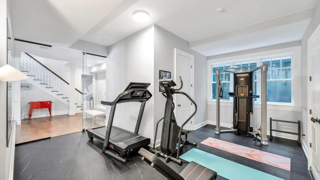 Un gimnasio en casa con máquinas de ejercicio y una ventana grande.