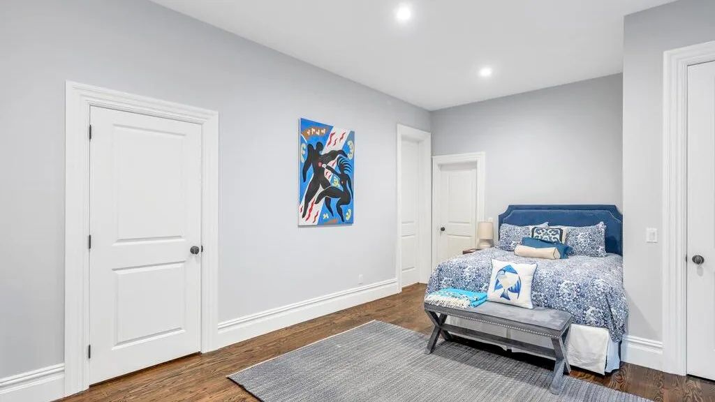 Un dormitorio con una cama azul y una alfombra gris en el suelo.