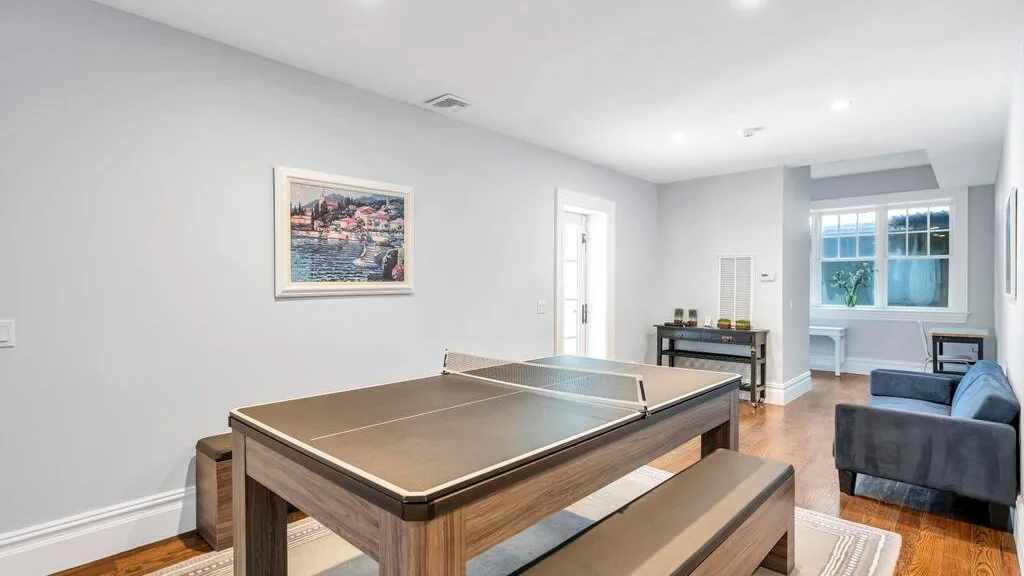 Una luminosa sala de juegos con una mesa de ping-pong y asientos.