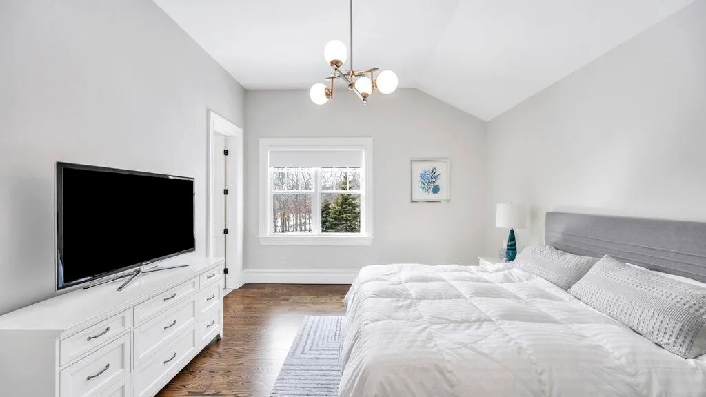 Un dormitorio luminoso con una cama grande, una cómoda y una ventana.