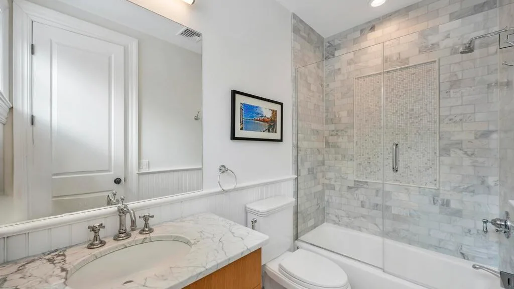 Un baño con un tocador de mármol y una ducha alicatada sobre la bañera.