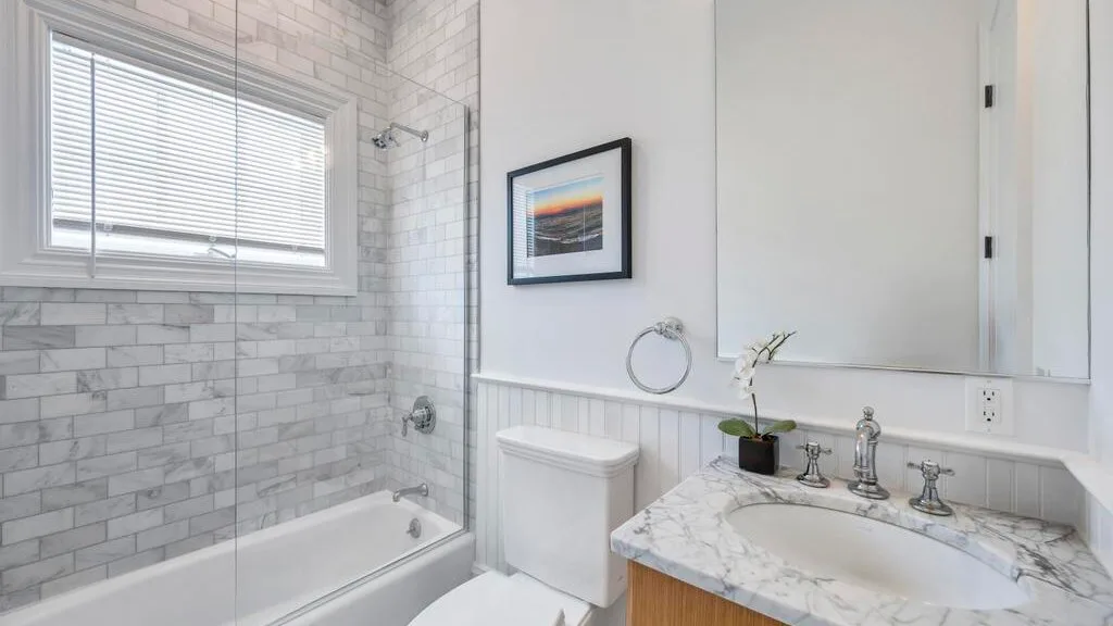 Un baño luminoso con bañera, paredes alicatadas y lavabo con mueble.