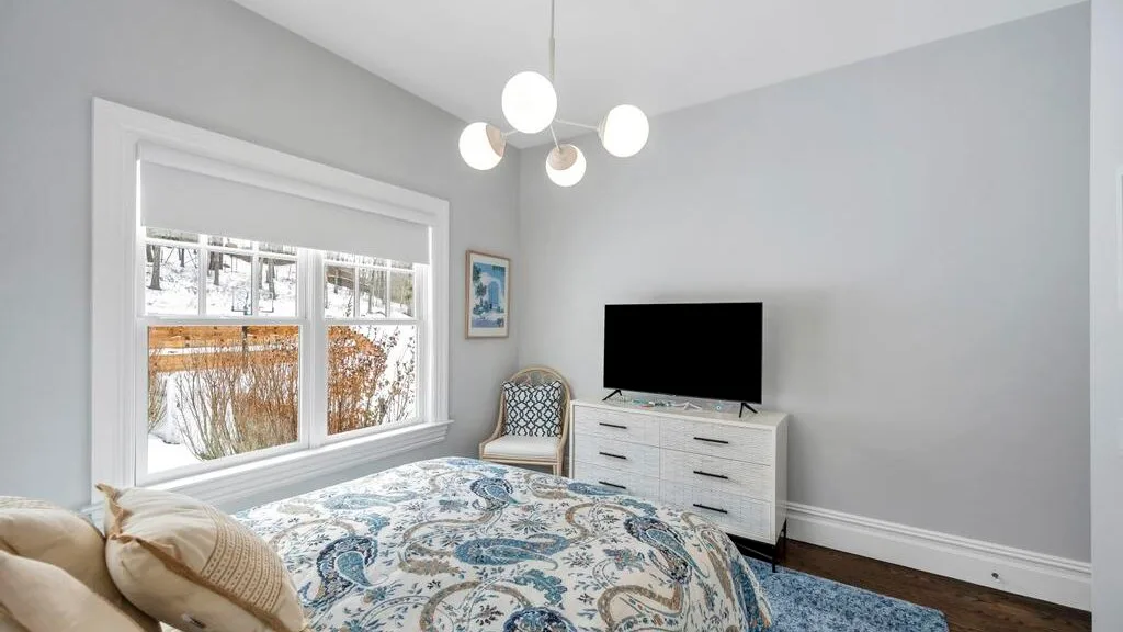 Un dormitorio con una colcha estampada, una cómoda y un televisor.