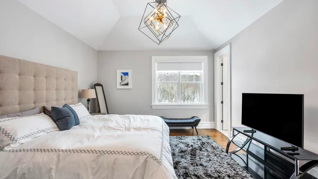 Un dormitorio luminoso con una cama grande, una ventana y un televisor.