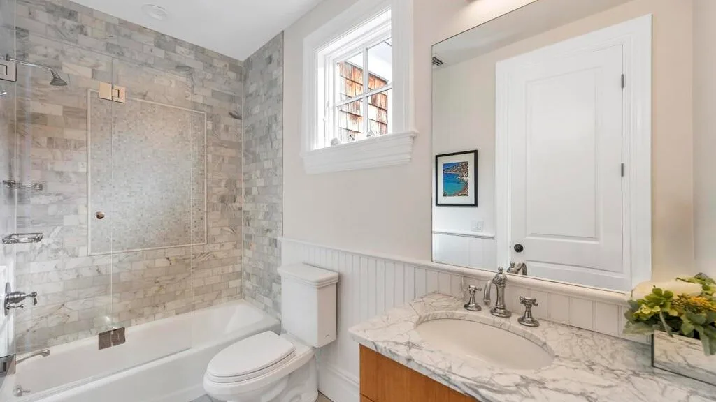 Un baño con bañera, inodoro y lavabo bajo un espejo.