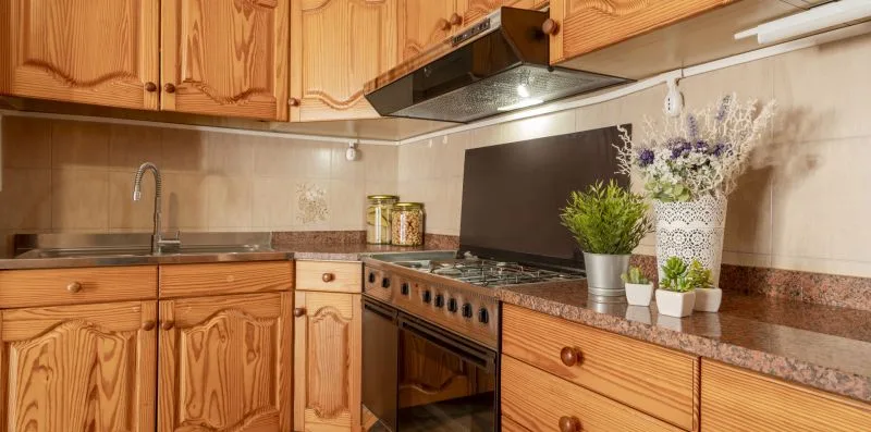 Una cocina con gabinetes de madera, una encimera y una estufa.