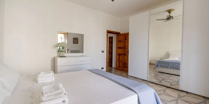 Un dormitorio luminoso con una cama, toallas dobladas y un armario con espejo.