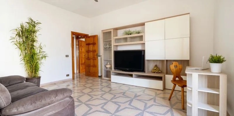 A bright living room with a television set into built-in shelving and a seating area.