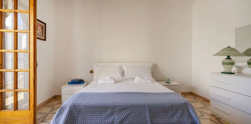 Un dormitorio con una cama tendida y una cómoda blanca.