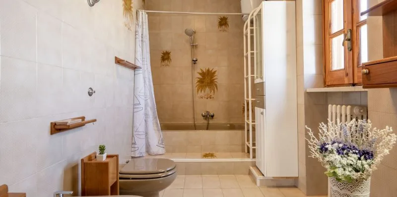 Un baño alicatado con bañera, ducha y ventana.