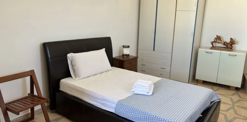 Un dormitorio con una cama, toallas dobladas y un armario.