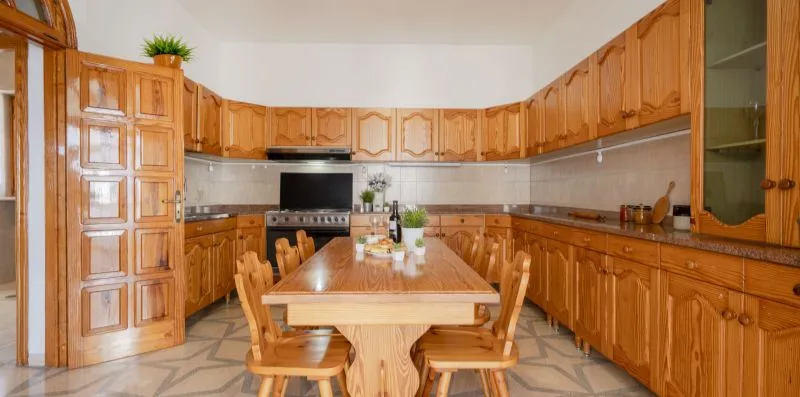 Una cocina y comedor con armarios de madera y una mesa rodeada de asientos.