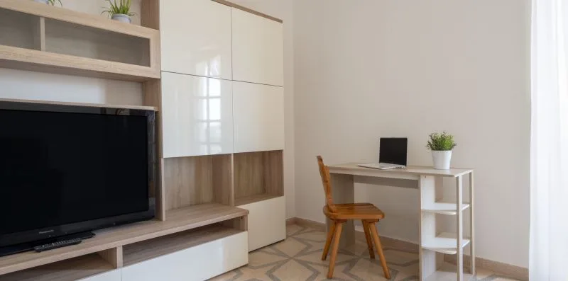 Una luminosa sala de estar con televisor y un pequeño escritorio junto a la ventana.