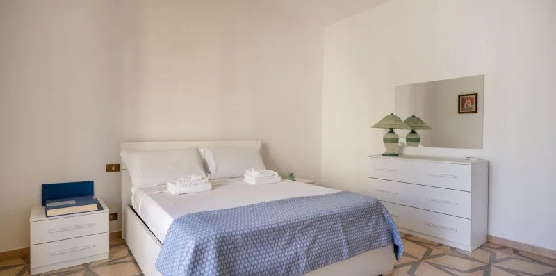 Un dormitorio con una cama bien tendida y una cómoda blanca.