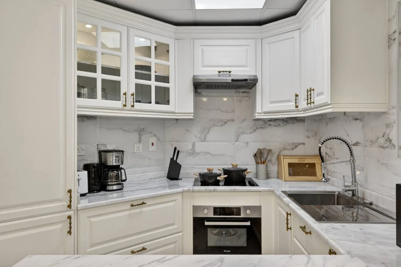 Una cocina blanca y luminosa con encimeras veteadas y un horno empotrado.