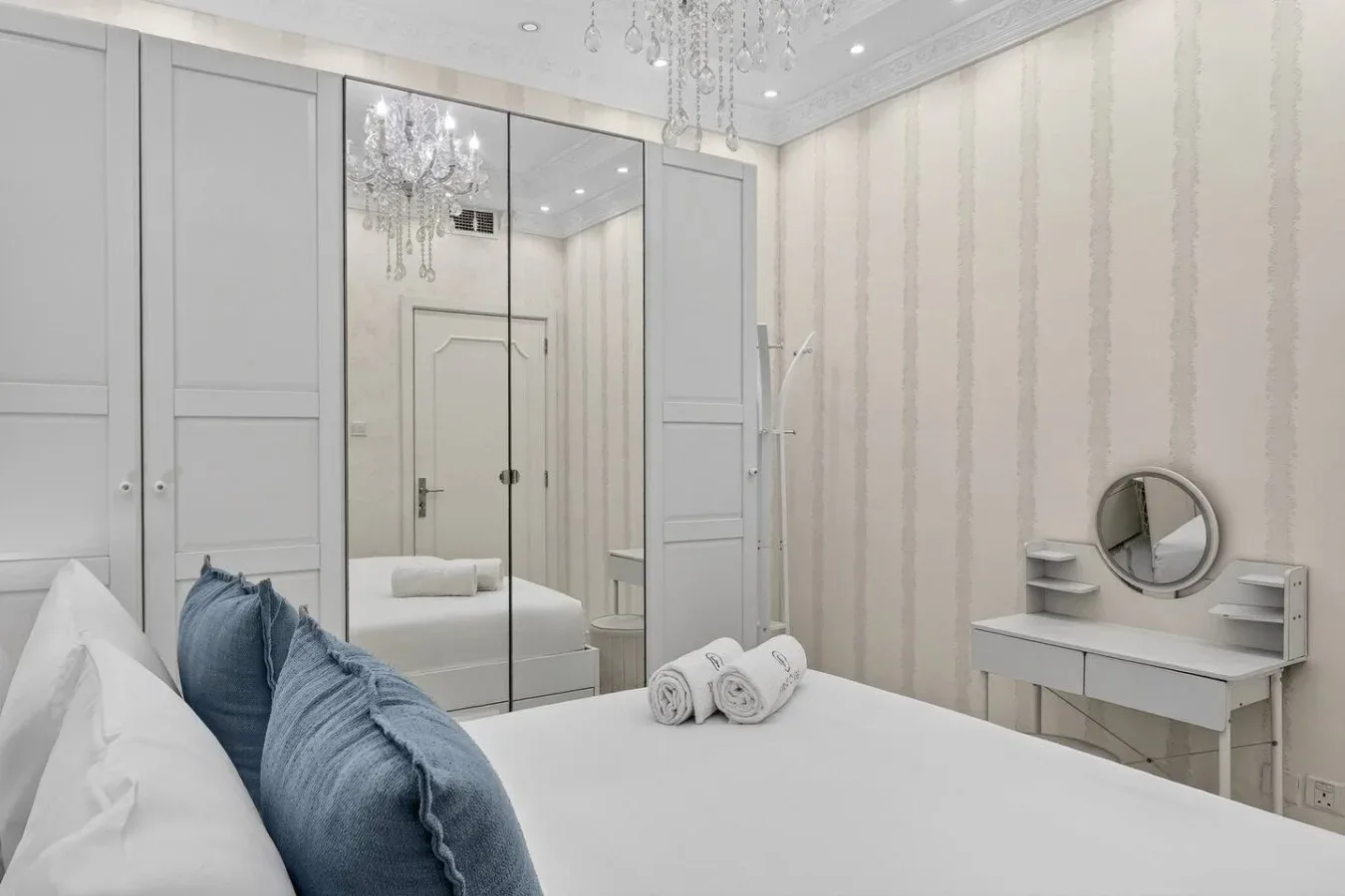 Un dormitorio luminoso con un armario con espejo y un pequeño tocador.
