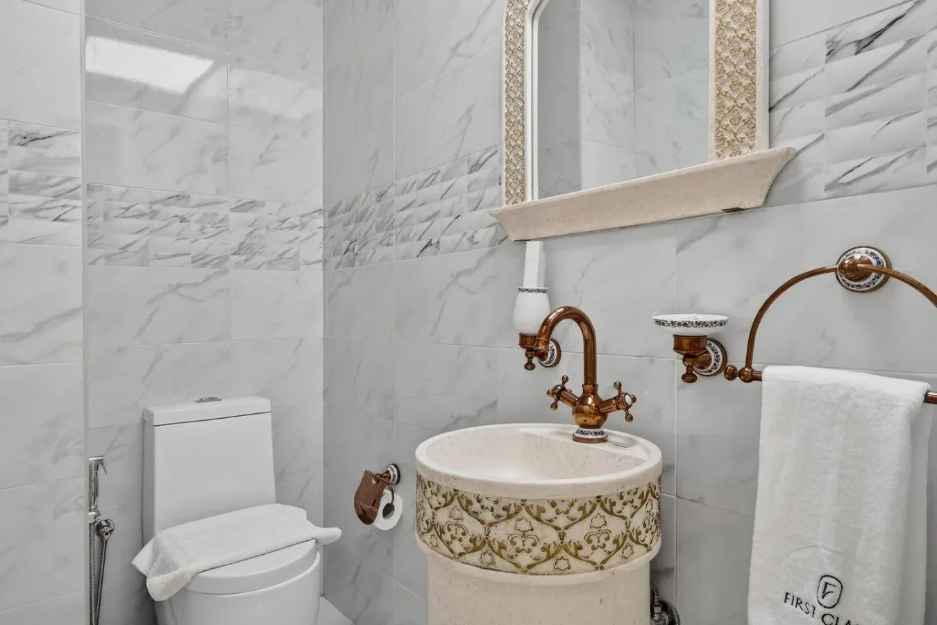 Un baño alicatado con un lavabo decorativo y una toalla colgada en la pared.