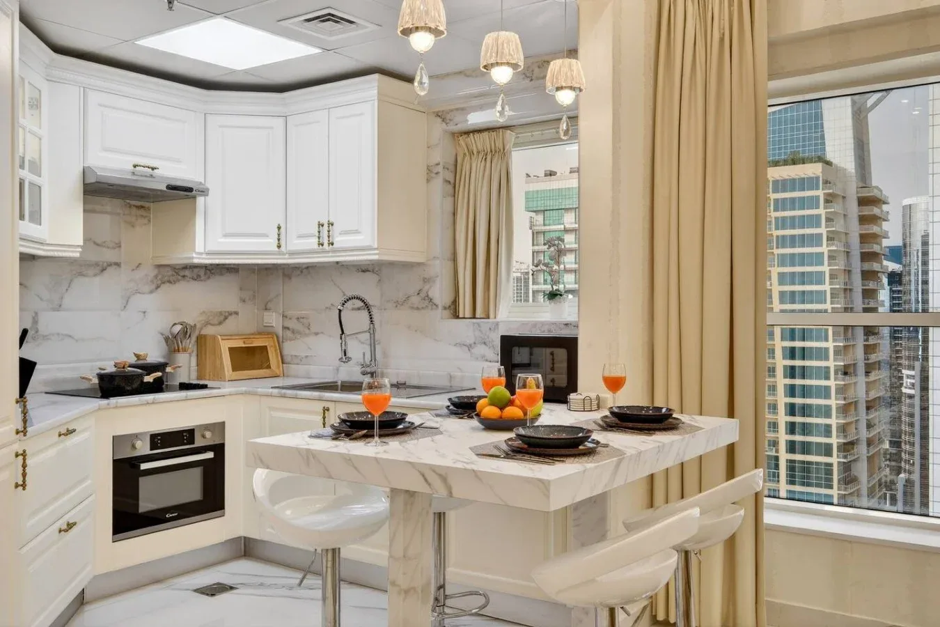 Una cocina luminosa con gabinetes blancos y una isla con cubierta de mármol.