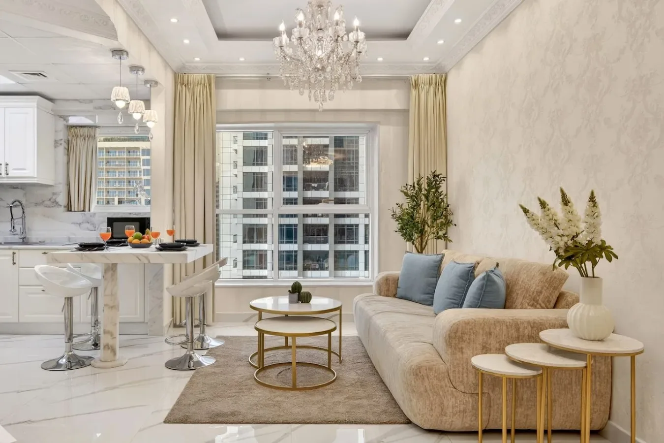 Una luminosa sala de estar con una zona de asientos beige junto a una cocina abierta.