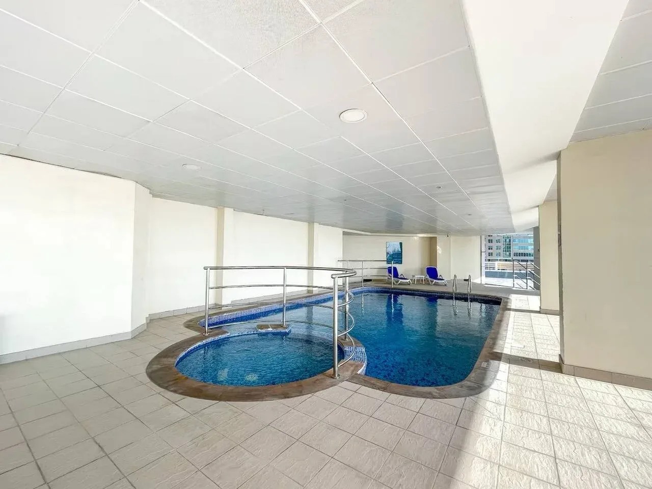 Una piscina cubierta con una pequeña sección redonda conectada a la piscina principal.