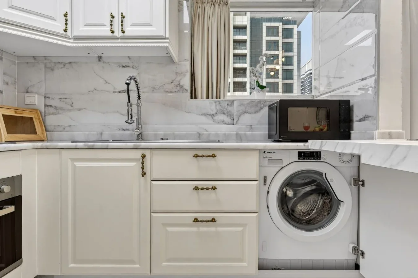 Una cocina luminosa con gabinetes blancos, un fregadero y una lavadora.
