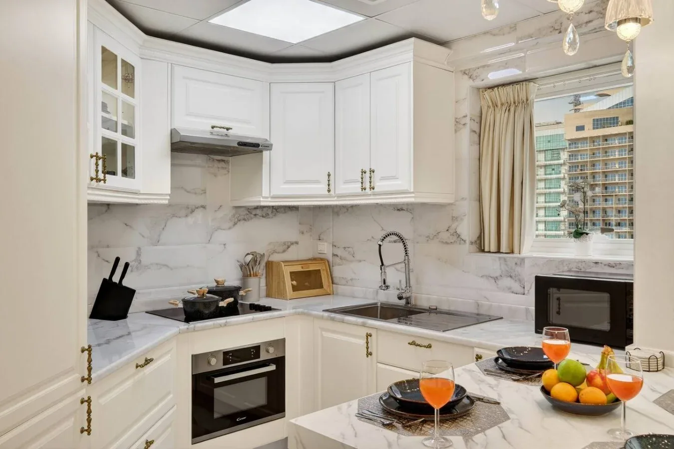 Una cocina luminosa con gabinetes blancos, encimera veteada y una isla para comer.