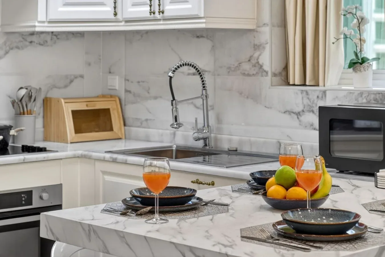 Una cocina luminosa con isla de mármol, fregadero y frutero.