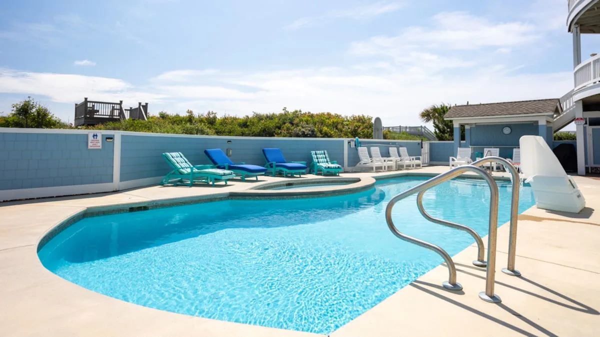 An outdoor swimming pool with lounge seating and a waterslide.
