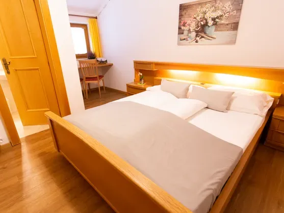 Habitación doble con cama de madera y zona de escritorio en el Almhotel Bergerhof