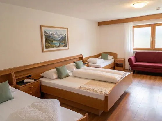 Amplia habitación familiar con sofá y una imagen de los Alpes en la pared, en el valle de Sarentino