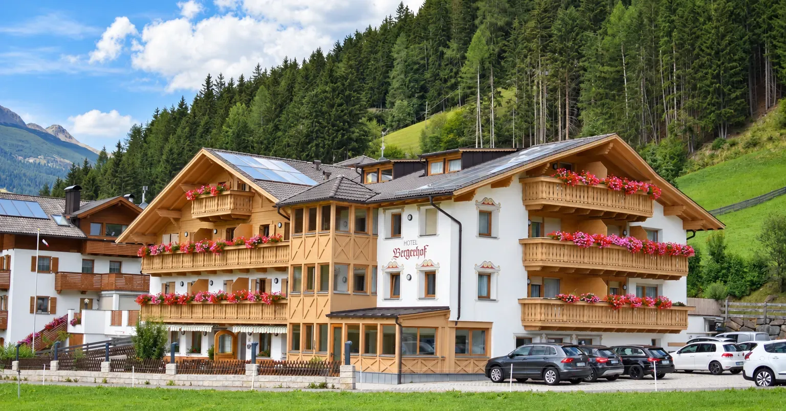 Almhotel Bergerhof con balcones de madera en una soleada ubicación de montaña en el valle de Sarentino