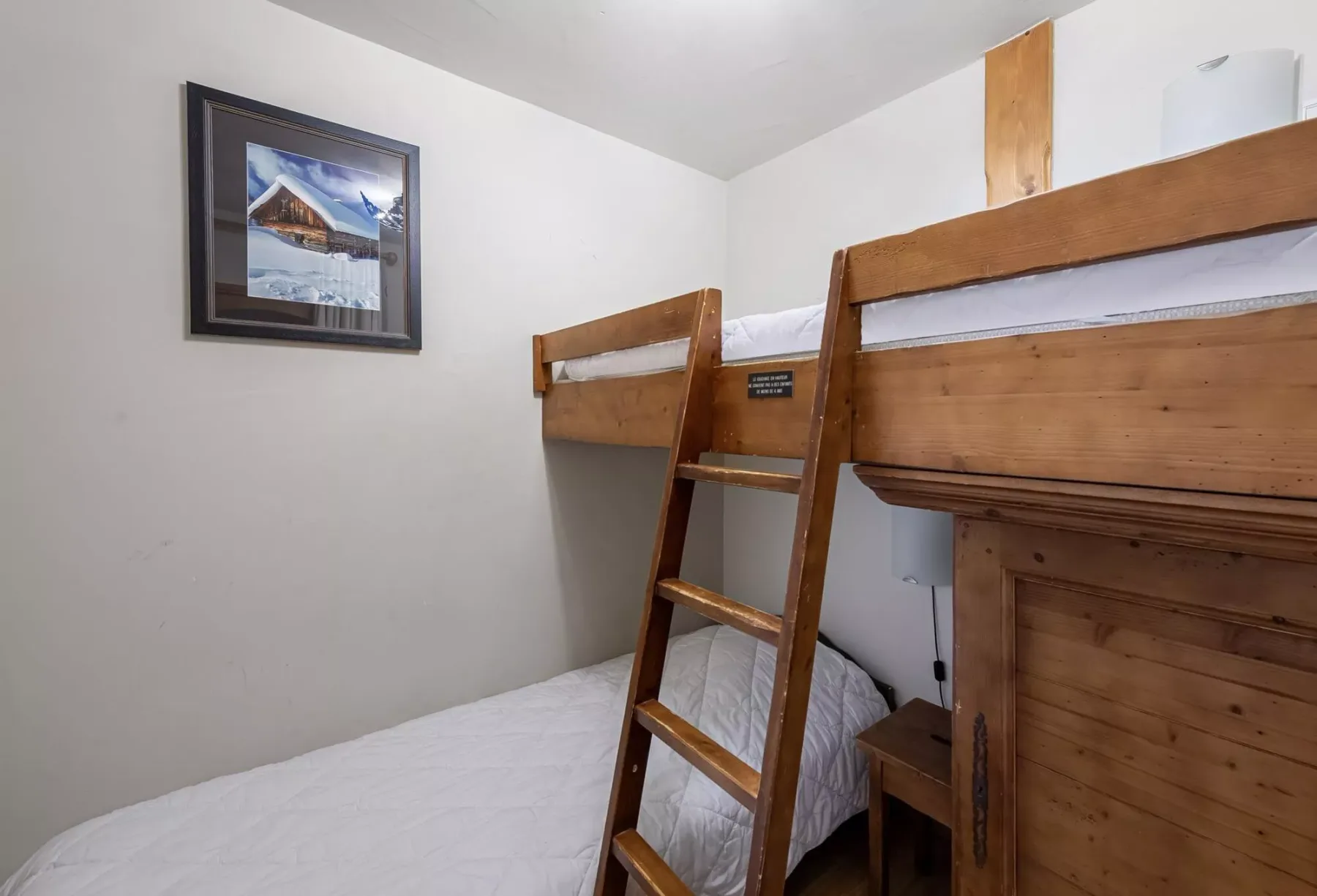Un dormitorio compacto con una litera de madera y un cuadro en la pared.